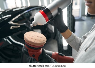 Professional detailer preparing electric buffer for car polishing - Powered by Shutterstock