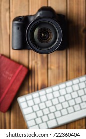 Professional digital camera and computer keyboard on wooden table.