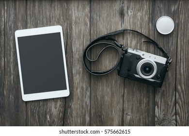 Professional digital camera and a touch screen tablet on a wooden desktop, hipster style