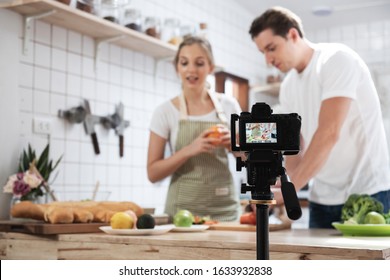 Professional digital mirrorless camera  recording video blog of happy caucasian couple cooking in the kitchen room, Camera for photographer or video and live streaming concept,Vlogger and blogger. - Shutterstock ID 1633932838