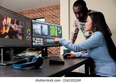 Professional digital movie editor sitting at desk while improving film frames and improving footage quality. Post production house team leader talking with coworker about quality of frames.