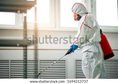 professional disinfector in protective suit holding chemical sprayer and other equipment for sterilization and decontamination of viruses, infectious diseases. coronavirus, COVID-19 epidemic concept
