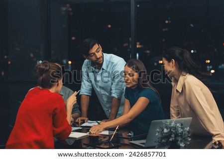Professional diverse businesspeople discussing about start up project. Manager explaining, sharing brainstorming business strategy at night office. Group of business team working together. Tracery.