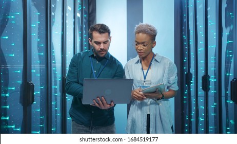 Professional Diverse Team Of Data Center Specialists Coworking In Server Room. Female And Male Engineers Inspecting Internet Database Servers At Computer Security. Teamwork.