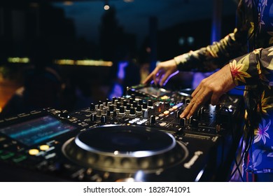 Professional dj playing music on rave party in night club.Hands of disc jockey mixing musical tracks on stage in club.Stage musical audio equipment in close up.Sound mixer & cd player turntables