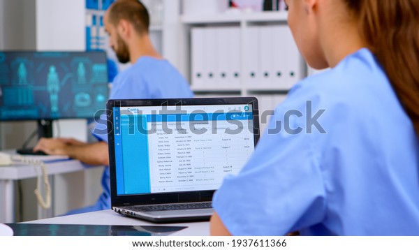 Professional doctor assistant checking\
medical records on laptop with x-ray and medical equipment around.\
Physician working in hospital clinic making appointments and\
analysing patient\
registration