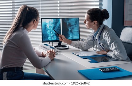 Professional doctor checking a patient's x-ray on the computer screen and pointing at the computer screen - Powered by Shutterstock