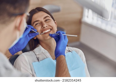 Professional doctor is checking woman's teeth in light modern dental clinic - Shutterstock ID 2182314245