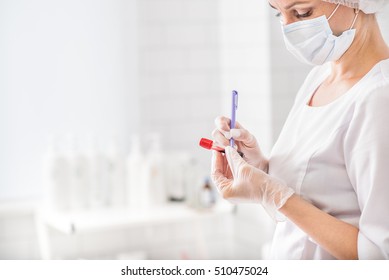 Professional Doctor Is Making Notes On Blood Sample With Concentration. Woman Is Standing In Lab