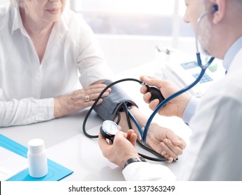 Professional Doctor Measuring Blood Pressure Of A Senior Female Patient During A Visit, Hypertension And Prevention Concept