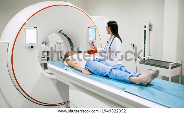 Professional Doctor\
Radiologist In Medical Laboratory Controls magnetic resonance\
imaging or computed tomography or PET Scan with Female Patient\
Undergoing\
Procedure.