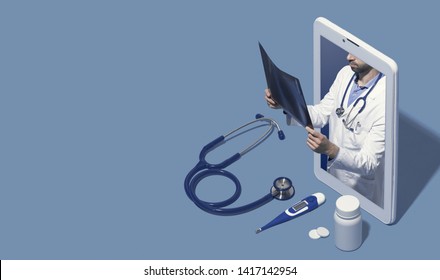 Professional doctor in a smartphone giving a consultation online and checking a radiography, telemedicine and healthcare concept, blank copy space - Shutterstock ID 1417142954