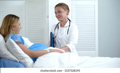 Professional doctor touching pregnant woman tummy, checking baby, healthcare