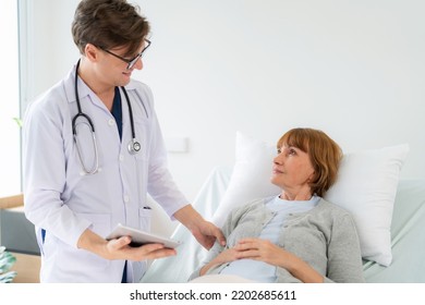 Professional Doctor In The White Coat Put A Stethoscope Around Neck Holding Tablet And Talked To
Elderly Woman Who Lying Down On The Bed At Nursing Home. Caregivers Provide Care Medical Service.