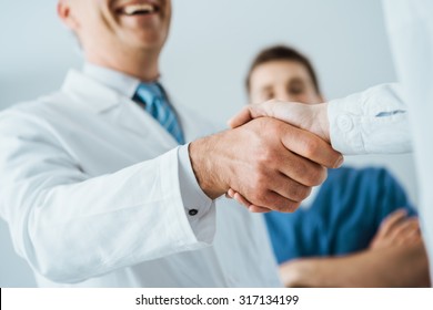 Professional doctors handshaking at hospital, hands close up, agreement and hiring concept