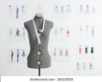 professional dressmakers dummy with measuring tape, with fashion sketches on wall behind
