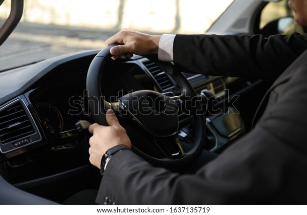 Professional driver in luxury car, closeup.\
Chauffeur service