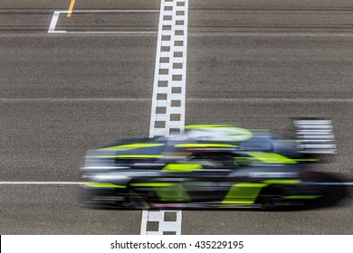 Professional driver race car racing on asphalt road speed track with motion blur crossing start and finish line, Automobile and automotive background concept.