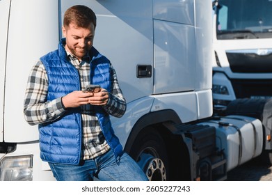 Professional driver using mobile phone while standing in front of his truck. Copy space.