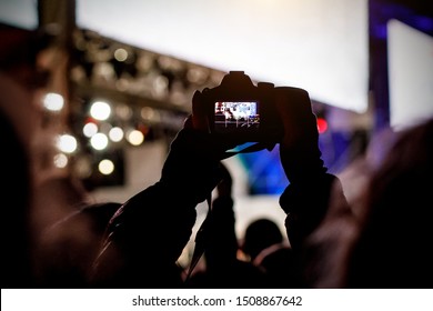 Professional dslr camera at music concert in raised up hand recording singer on a stage