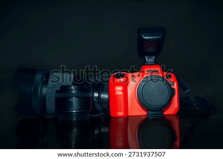 Professional DSLR camera with speedlight flash and lenses on a dark reflective surface.
