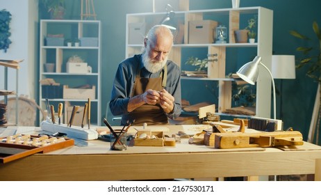 Professional Elderly Man Carpenter Working on Wood Using Carpentry Tools in the Garage. Craft Authentic Workshop. Handicraft, Creative Small Business. Profession, Art and Hobby Concept. - Powered by Shutterstock