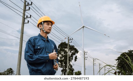 Professional electrical engineer inspecting wind turbine and power transmission lines for renewable energy infrastructure, sustainable electricity and green technology development.