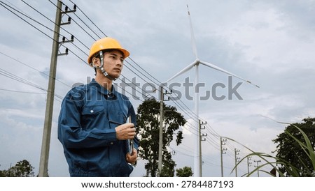 Professional electrical engineer inspecting wind turbine and power transmission lines for renewable energy infrastructure, sustainable electricity and green technology development.