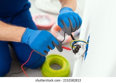 Professional electrician testing an outlet using a digital multimeter - Shutterstock ID 2152582813