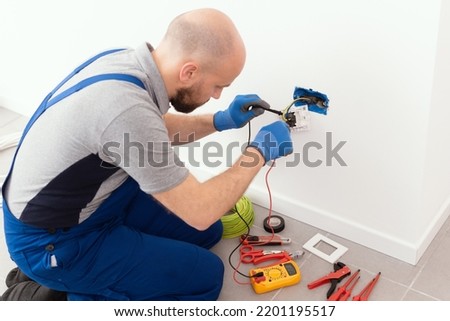 Professional electrician testing an outlet using a digital multimeter