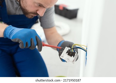 Professional electrician working on a home electrical system, he is installing a wall socket - Shutterstock ID 2171950187