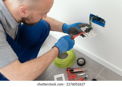 Professional electrician working on a home electrical system, he is installing a wall socket