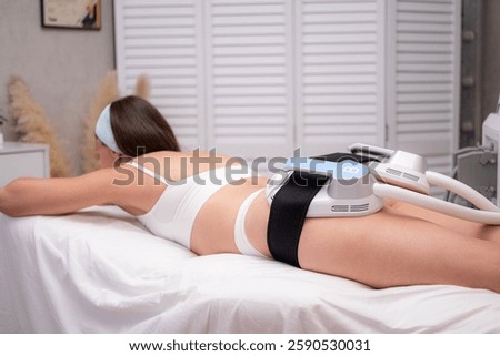 professional electrostimulation session, close up view o therapist applying EMS device on woman in modern clinic, muscle toning, body sculpting, fitness industry