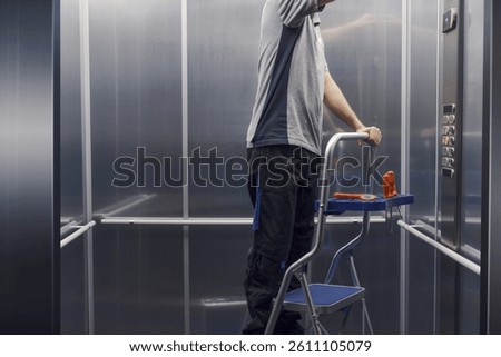 Professional elevator mechanic at work, he is checking and repairing the elevator
