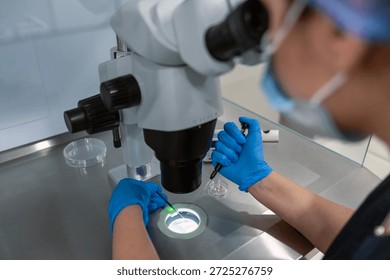 Professional embryologist using microscope for ICSI IVF procedure, microinjection of sperm into female egg cell in fertility clinic laboratory for assisted reproduction, human artificial insemination.