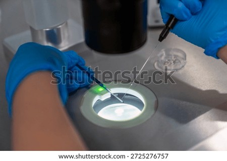 Professional embryologist using microscope for ICSI IVF procedure, microinjection of sperm into female egg cell in fertility clinic laboratory for assisted reproduction, human artificial insemination.
