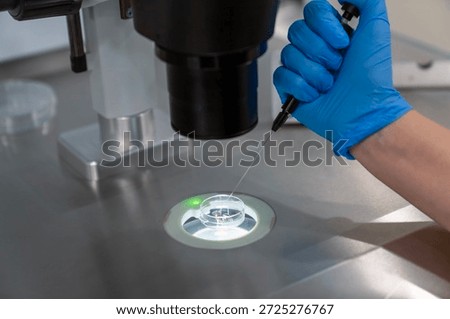 Professional embryologist using microscope for ICSI IVF procedure, microinjection of sperm into female egg cell in fertility clinic laboratory for assisted reproduction, human artificial insemination.