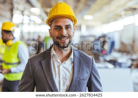 Professional engineer in a construction setting, wearing a hard hat and suit, showcasing confidence and leadership. The workplace background emphasizes an industrial and professional environment.