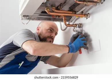 Professional engineer installing a natural gas boiler at home, he is checking the pipes - Shutterstock ID 2159556829