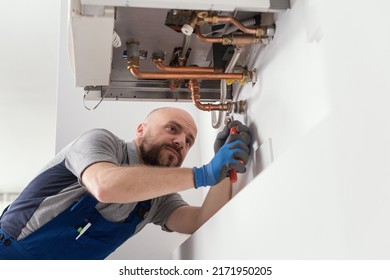 Professional Engineer Installing A Natural Gas Boiler At Home, He Is Checking The Pipes