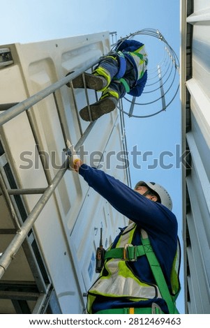 Professional engineer performs routine inspection on rooftop cooling tower. Worker uses safety harness, hard hat, ensuring protection during critical HVAC system maintenance operations.