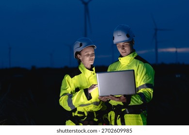 Professional engineer team working at night shift. Workers teamwork in wind turbine field. Technician technology expert work with safety dress survey inspecting outdoor.