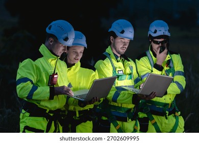 Professional engineer team working at night shift. Workers teamwork in wind turbine field. Technician technology expert work with safety dress survey inspecting outdoor.