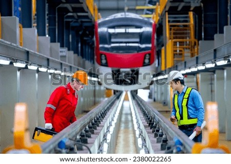 Professional engineer and technician workers discuss and stay in front of train to check function of railroad tracks of electrical or sky train in factory workplace.