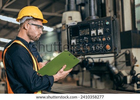 professional engineer working reading user manual control operate program CNC milling machine in heavy industry factory