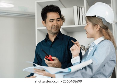 Professional Engineers Discussing Architectural Plans in Modern Office Setting with Blueprints and Safety Gear - Powered by Shutterstock