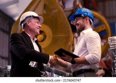 Professional engineers wear white and blue helmet for security safety in Metal Lathe heavy factory, shaking hands after deal agreement complete to produce the products and supplying the material - Shutterstock ID 2176043747