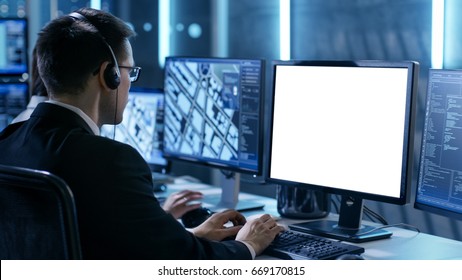 Professional IT Engineers Working In System Control Center Full Of Monitors And Servers. Possibly Government Agency Conducts Investigation. He Works With White Screen Isolated. Good For Template.