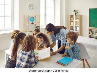 Professional enthusiastic young female teacher reading story with diverse group of happy active elementary school pupils in classroom. Learning lesson, back to school and primary education concept