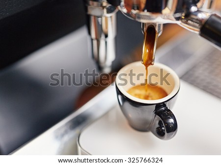 Professional espresso machine pouring strong looking fresh coffee into a neat ceramic cup